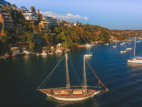 Wooden sailboat and luxury waterfront properties in the distance - Sydney, Australia